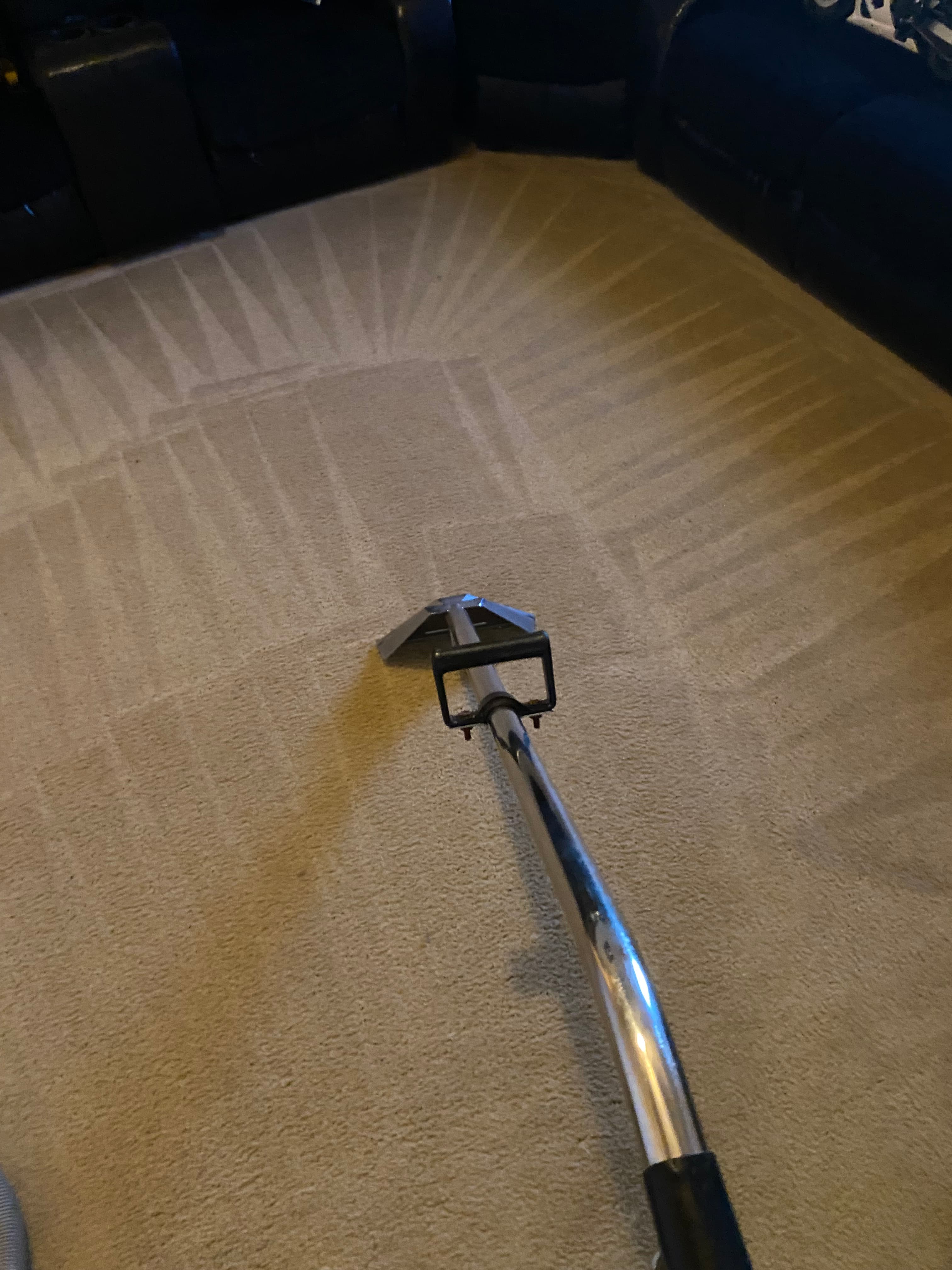 Metal steam cleaner wand on beige carpet showing distinct triangular cleaning strokes and patterns.