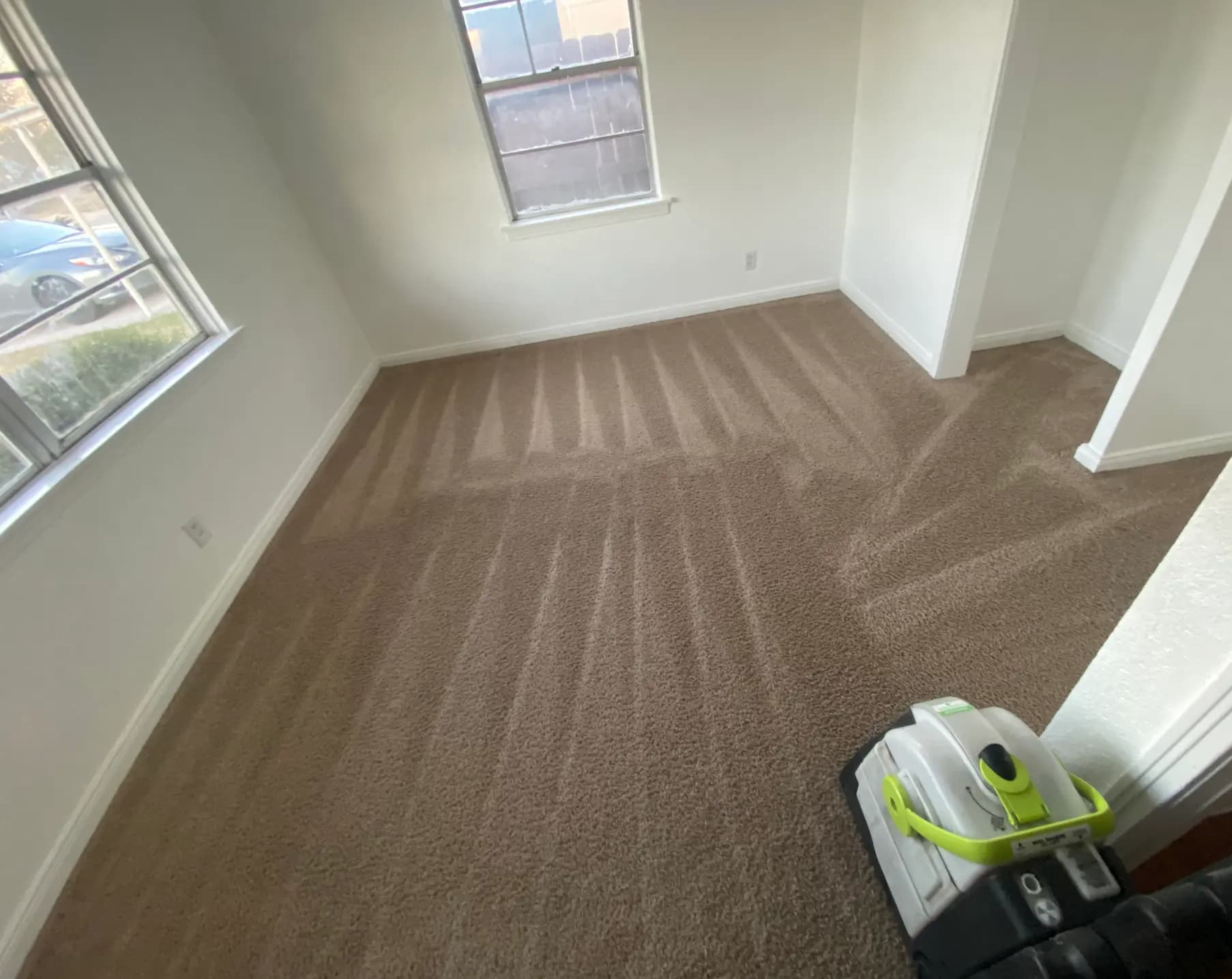 Freshly cleaned brown carpet with triangular vacuum patterns in a room with white walls.